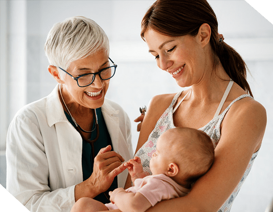 Smiling doctor examines a baby held by a smiling woman.