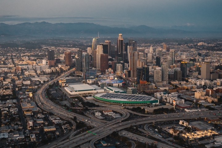 Aerial view of a city skyline with highways and buildings under a clear sky.